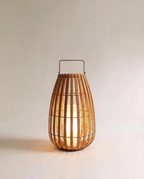 Clérachic slatted natural-fibre floor lantern with a metal top handle, lit softly by an inner pillar light, medium size.