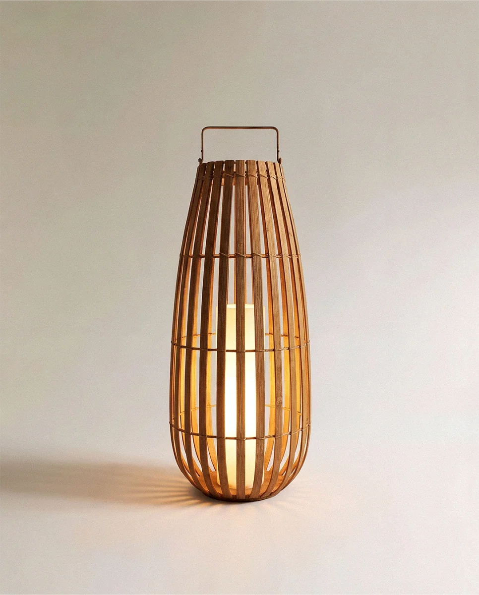 Clérachic tall slatted natural-fibre floor lantern with a slim handle and a glowing inner pillar light, large size.