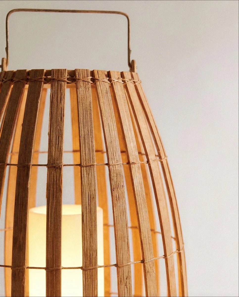 Close view of the Clérachic lantern top, showing the slim metal handle and slats lashed with fine cord, lit from inside.