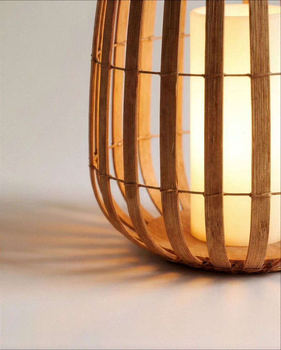 Close view of the Clérachic lantern base, where curved slats meet a round wooden floor and a glowing pillar light casts shadows.
