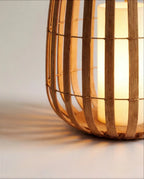 Close view of the Clérachic lantern base, where curved slats meet a round wooden floor and a glowing pillar light casts shadows.