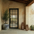 Pair of Clérachic slatted lanterns with pillar candles on a stone porch beside a blue-glazed urn and a glazed iron door.