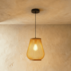 Clérachic slatted teardrop pendant light, larger size, glowing amber on a black cord and canopy against limewashed plaster.