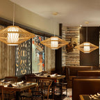 Clérachic flared slatted pendant lights hanging in a restaurant above wooden tables, lit warm against dark panelling.