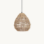 Natural woven rattan teardrop pendant from Clérachic on a black cord, shown on a plain off-white backdrop.