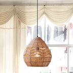 Woven Clérachic teardrop pendant glowing warm in front of a sunlit window with cream swag curtains.