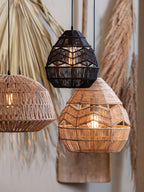 A black and a natural Clérachic woven pendant hang with a third rattan shade against dried palm and pampas.
