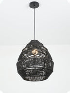 Black Clérachic woven pendant, lit, hanging from a round black canopy against a plain white wall.