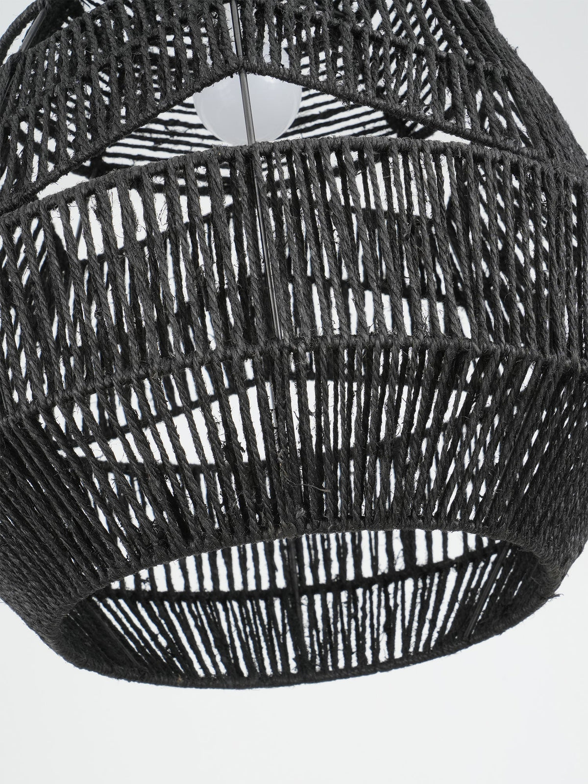 Close view looking up into the open black woven shade of this Clérachic pendant, with the bulb at the top.