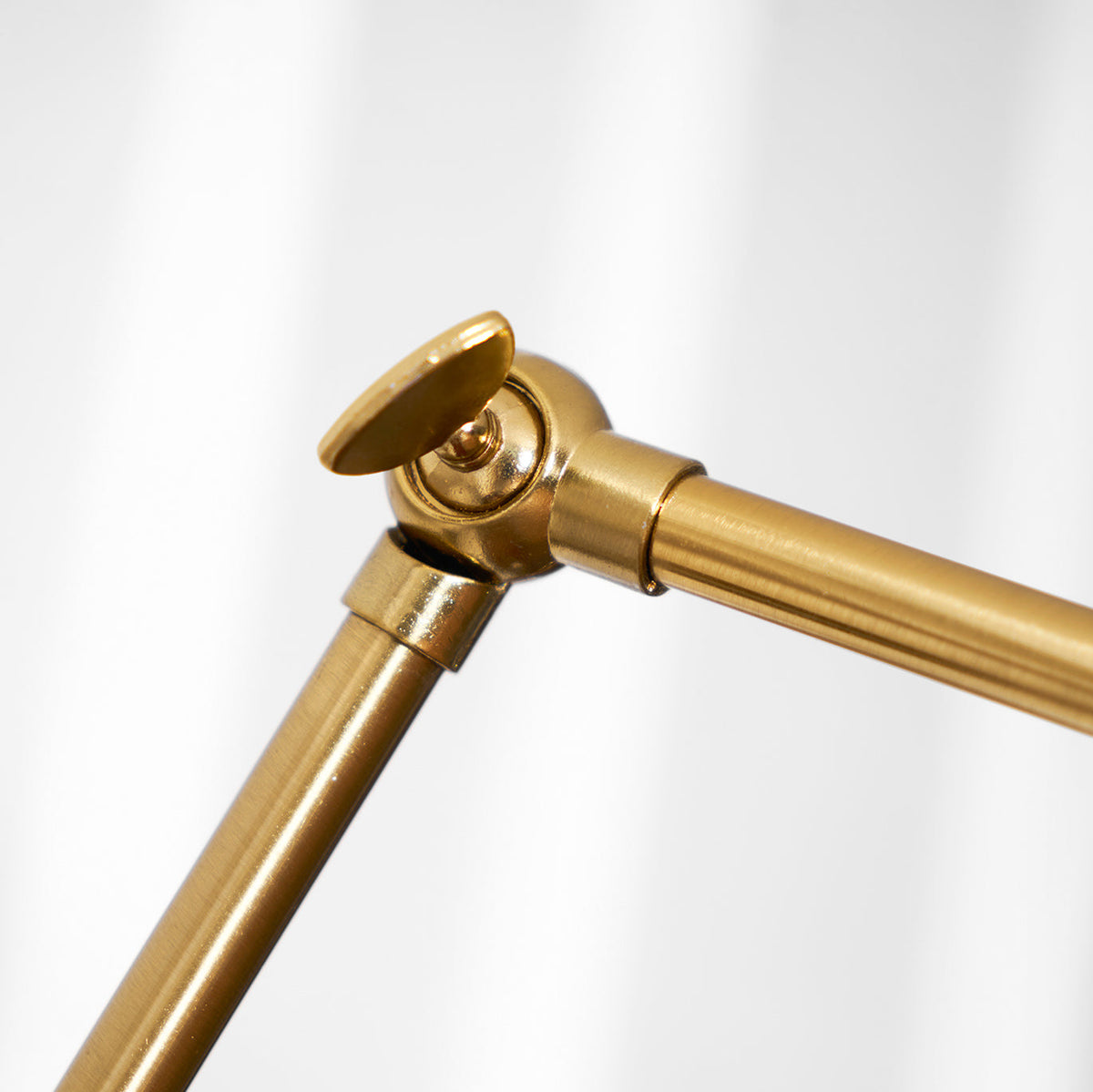 Close view of the knuckle joint and brass tubing on the adjustable arm of this Clérachic wall light.