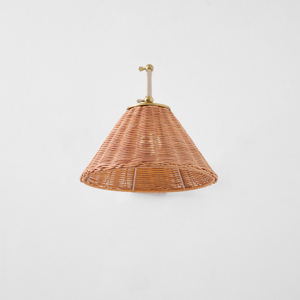 A full underside view of the woven rattan cone shade on this Clérachic wall light, with the gold arm folded above it.