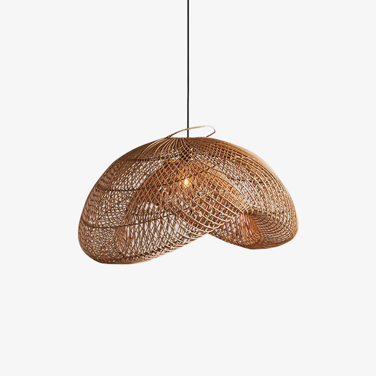 A Clérachic rattan pendant with an open-weave wave-shaped shade and a black cord, on a plain white backdrop with a small bulb glowing inside.