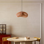 Warm-toned Clérachic open-weave pendant hung above a round table with mustard chairs, against a softly panelled cream wall.
