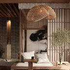 This Clérachic rattan pendant over a daybed in a timber-ceilinged room with slatted screens, an olive tree and a brush-ink painting.