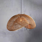 Close view of the open weave on this Clérachic rattan pendant, hung against a textured grey concrete wall with its wire rim showing.