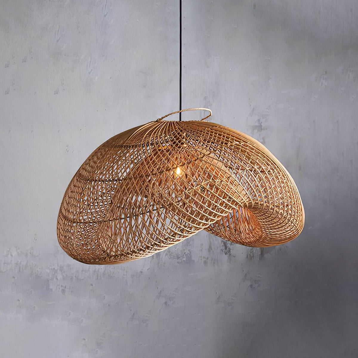 Close view of the open weave on this Clérachic rattan pendant, hung against a textured grey concrete wall with its wire rim showing.