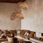 A pair of Clérachic rattan wave pendants in a warm living room, hung in front of a lime-washed wall above a corner sofa.