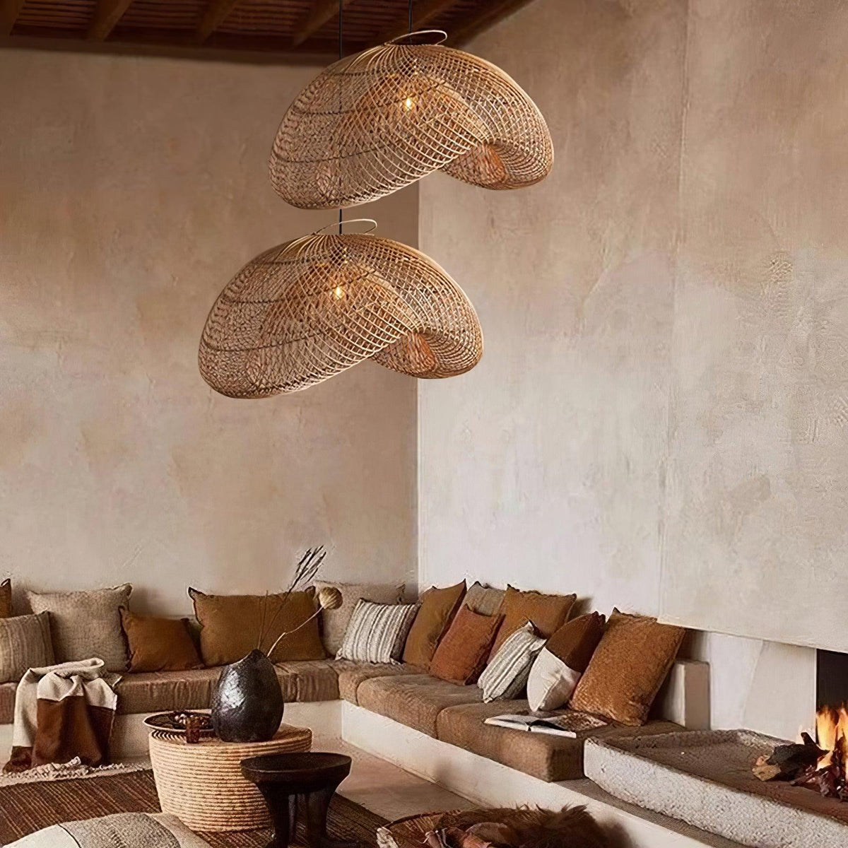A pair of Clérachic rattan wave pendants in a warm living room, hung in front of a lime-washed wall above a corner sofa.