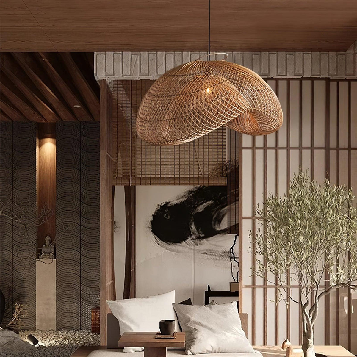A Clérachic rattan pendant hanging in front of a slatted screen and olive tree, over a low seat with white cushions.