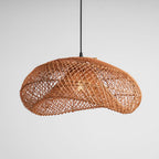 Clérachic rattan wave pendant on a pale grey backdrop, seen from a slight angle with the open weave catching the light.