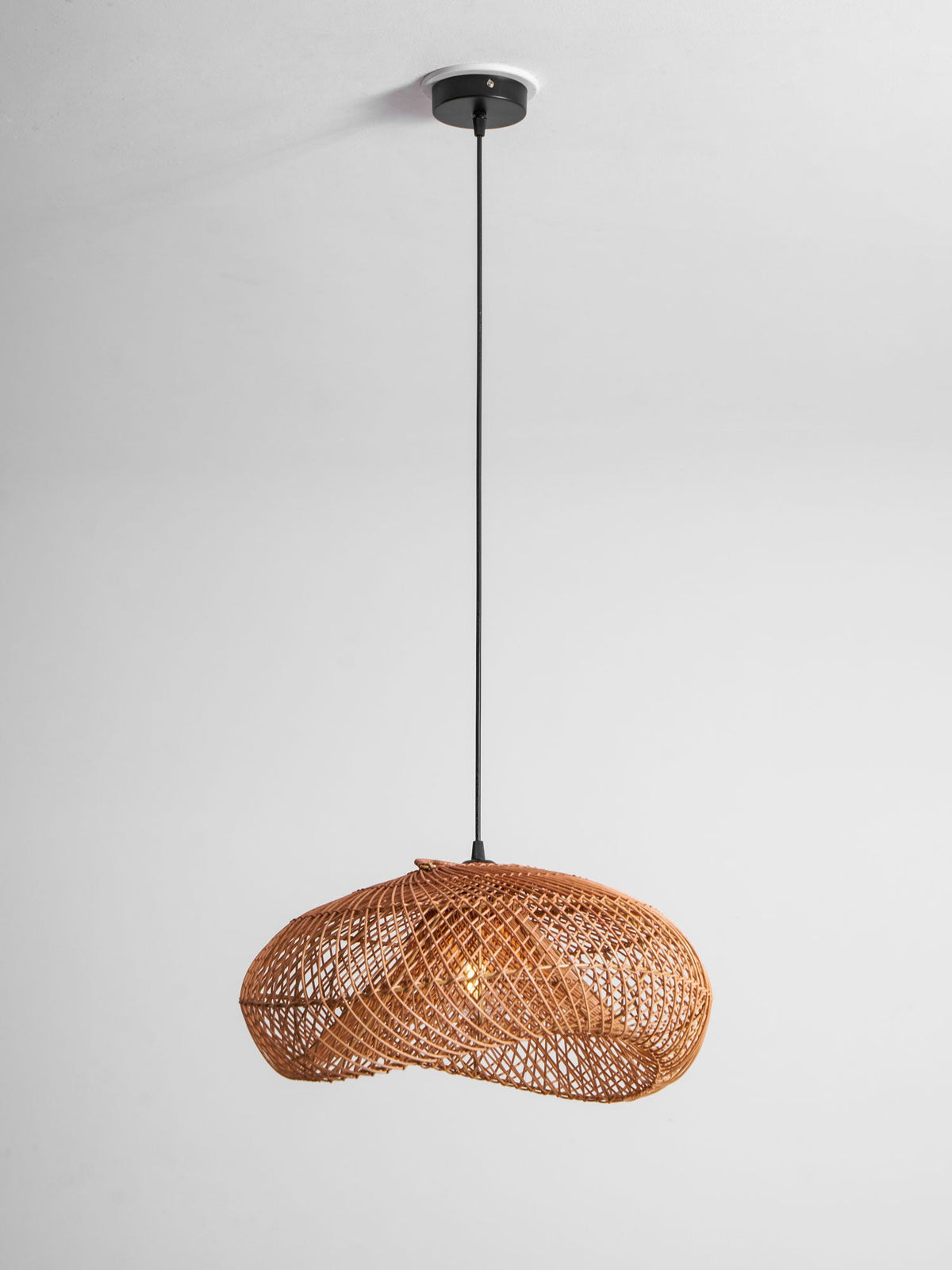 Full-length view of this Clérachic rattan pendant on a ceiling plate with a long black cord, against a pale grey wall.