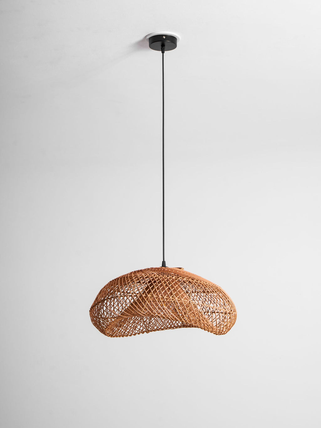 This Clérachic pendant on a long black cord, tilted slightly, with the woven shade hanging well below a small round ceiling plate.
