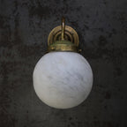 The Clérachic sconce seen head on, its brass gallery ring and fixing screws sitting neatly on top of the globe.