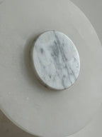 Clérachic wall lamp in close-up, its grey-veined white marble disc standing proud of the milky alabaster backplate.