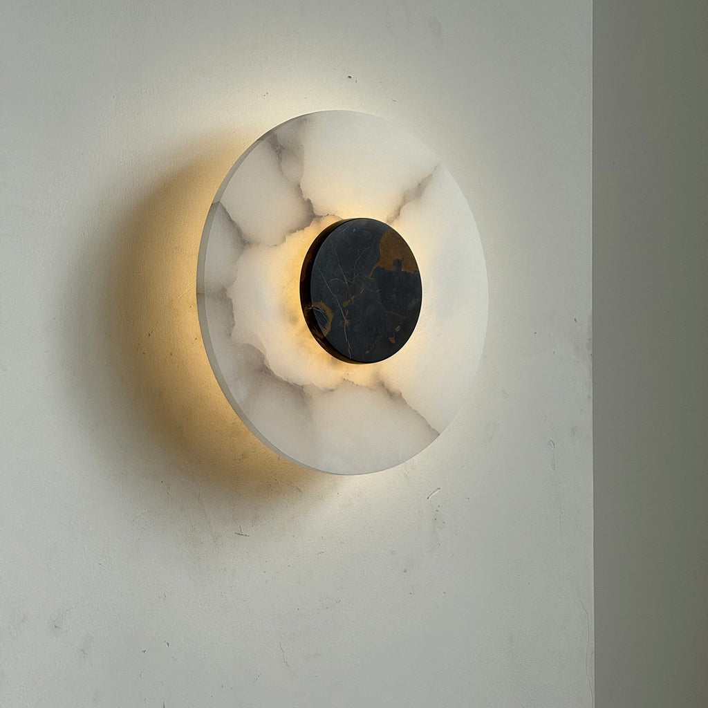 The Clérachic wall lamp lit from the side, its glow washing the wall while brown veins show through the alabaster.