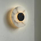 The Clérachic wall lamp lit from the side, its glow washing the wall while brown veins show through the alabaster.
