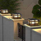 Three Clérachic Ray pillar lights lit along a rendered garden wall beside a metal gate.