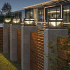 Four Clérachic Ray pillar lights lit along a boundary wall outside a low modern building.