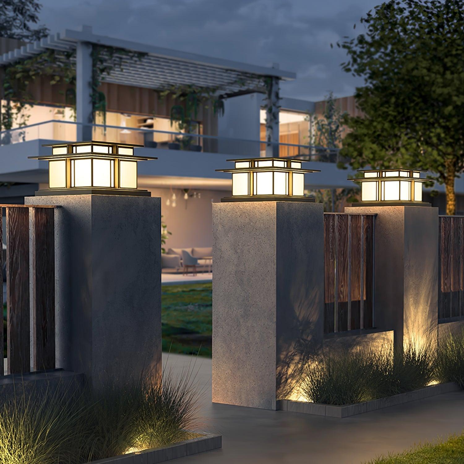 Three Clérachic Ray pillar lights lit on stone piers at the entrance to a garden terrace.