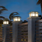Clérachic Ray pillar lights glowing on posts against a dusk sky with palms behind.