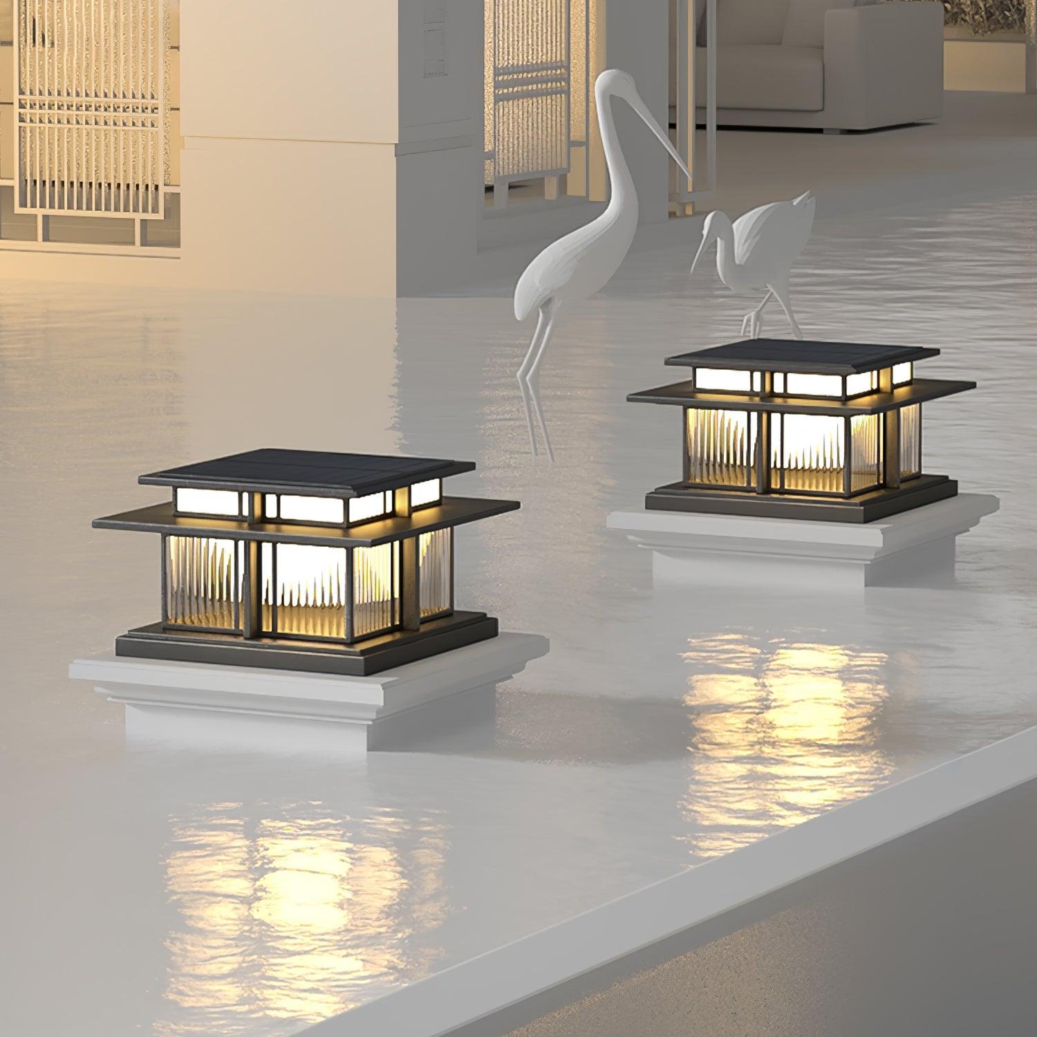 Two Clérachic Ray pillar lights lit at a poolside terrace, reflections across the water.