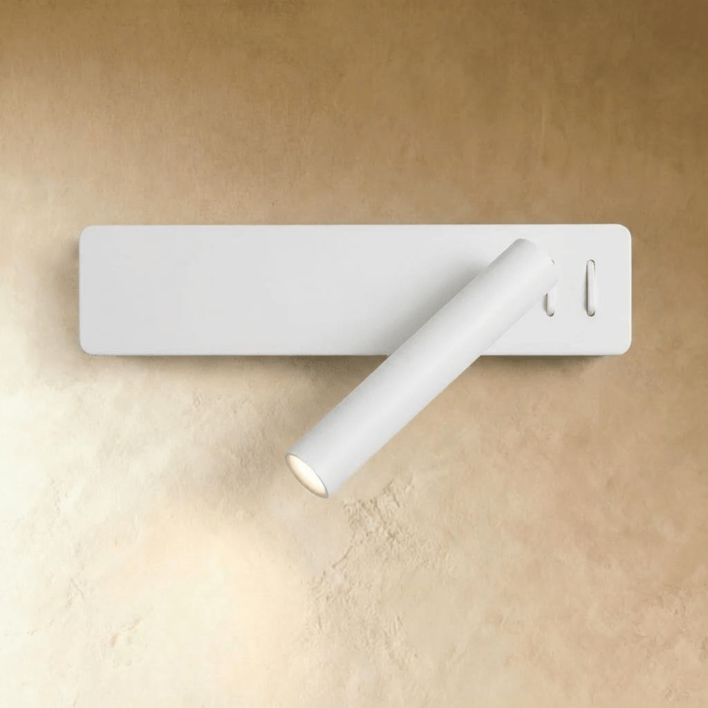 Clérachic white wall reading light with a slim rectangular backplate and angled cylindrical arm, glowing against a plaster wall.