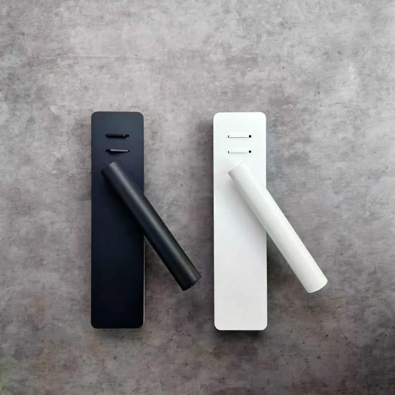 Two Clérachic reading wall lights, one matte black and one white, laid side by side with their cylindrical arms angled out.