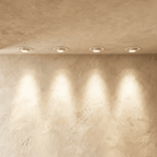 Clérachic white recessed tilting downlights set in a limewash ceiling, each washing a warm pool of light down the wall.