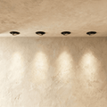 Clérachic black recessed tilting downlights in a limewash ceiling, angled to throw soft pools of light onto the wall.