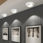 Clérachic white recessed tilting downlights in three sizes, angled to graze a slatted grey wall above framed prints.
