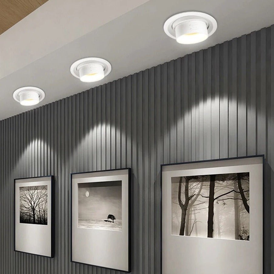 Clérachic white recessed tilting downlights in three sizes, angled to graze a slatted grey wall above framed prints.