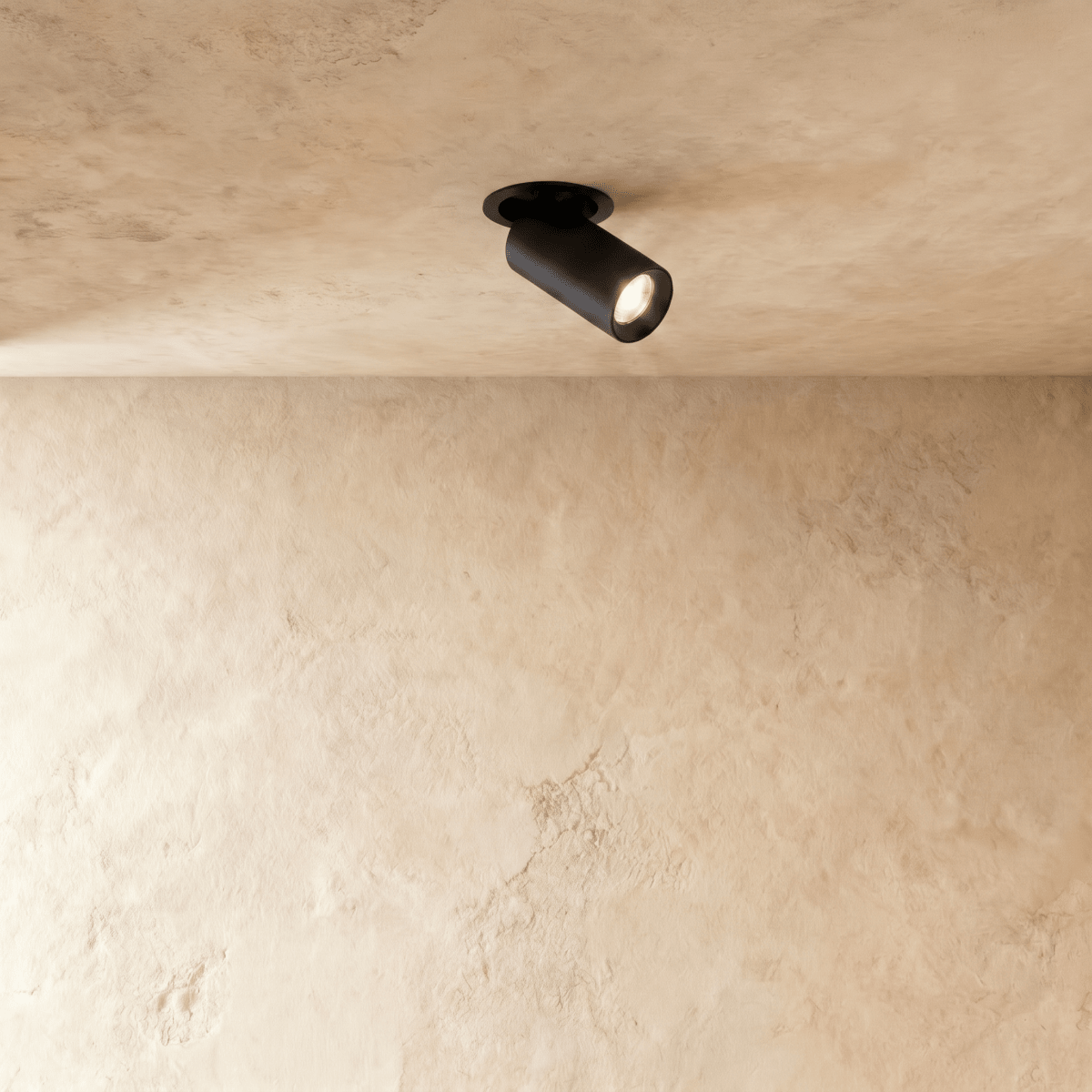 Clérachic recessed downlight in matt black, the pivoting cylindrical head glowing warm against a pale limewashed plaster ceiling.