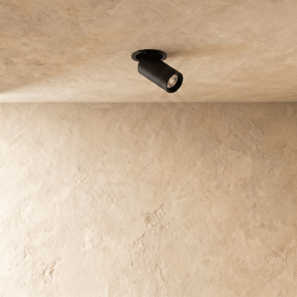 Clérachic black recessed spotlight with a round flush trim, angled head switched on, set in a textured cream plaster ceiling.