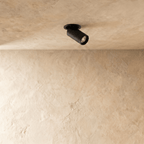 Clérachic black recessed spotlight with a round flush trim, angled head switched on, set in a textured cream plaster ceiling.