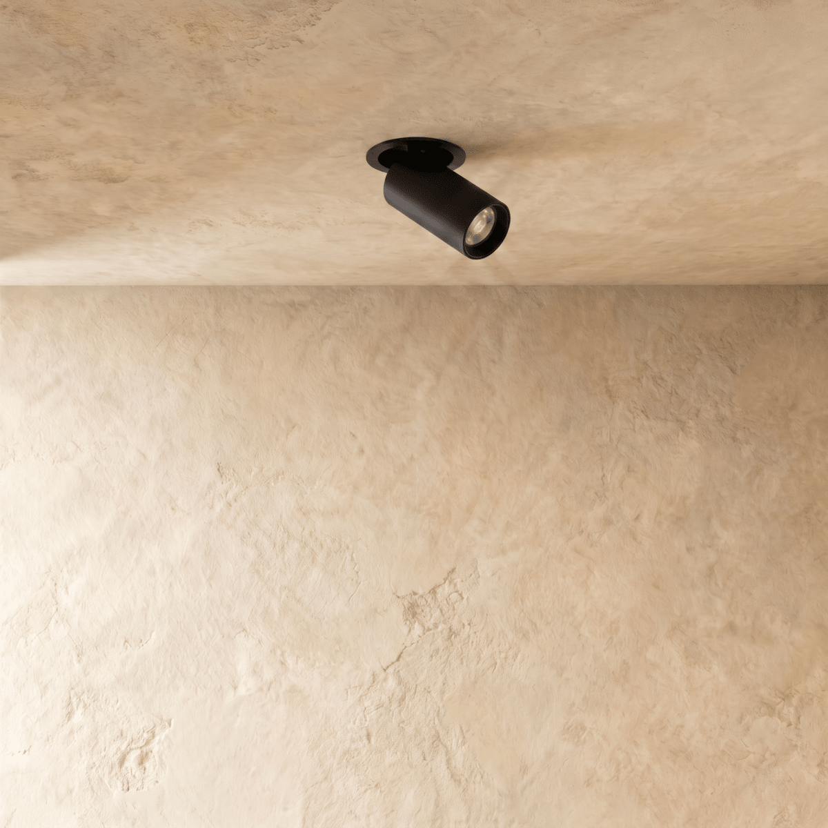 Clérachic black recessed spotlight with a round flush trim, angled head switched on, set in a textured cream plaster ceiling.