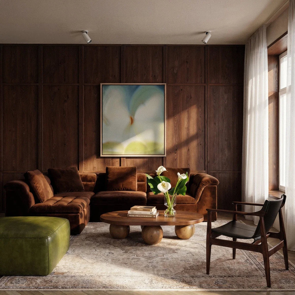Clérachic white spotlights on the ceiling of a dark wood-panelled living room with a velvet sofa, round table and calla lilies.