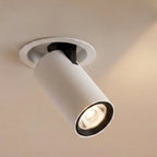 Close view of a Clérachic white recessed downlight, cylindrical head tilted from a round trim, black inner ring and warm beam.
