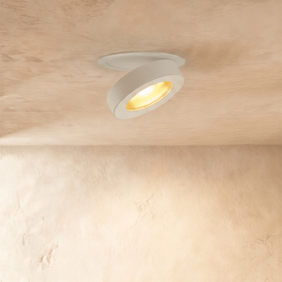 Clérachic recessed downlight in white, turned to aim along the wall with the gold-toned reflector glowing warm inside the ring.