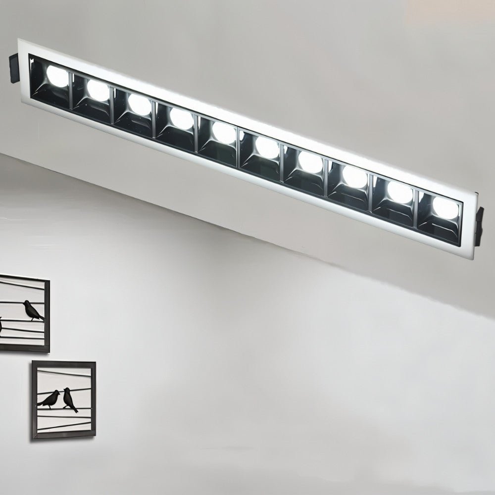 Clérachic ten-head recessed linear downlight in a slim white frame, its cool white LEDs lit above a grey wall with bird prints.