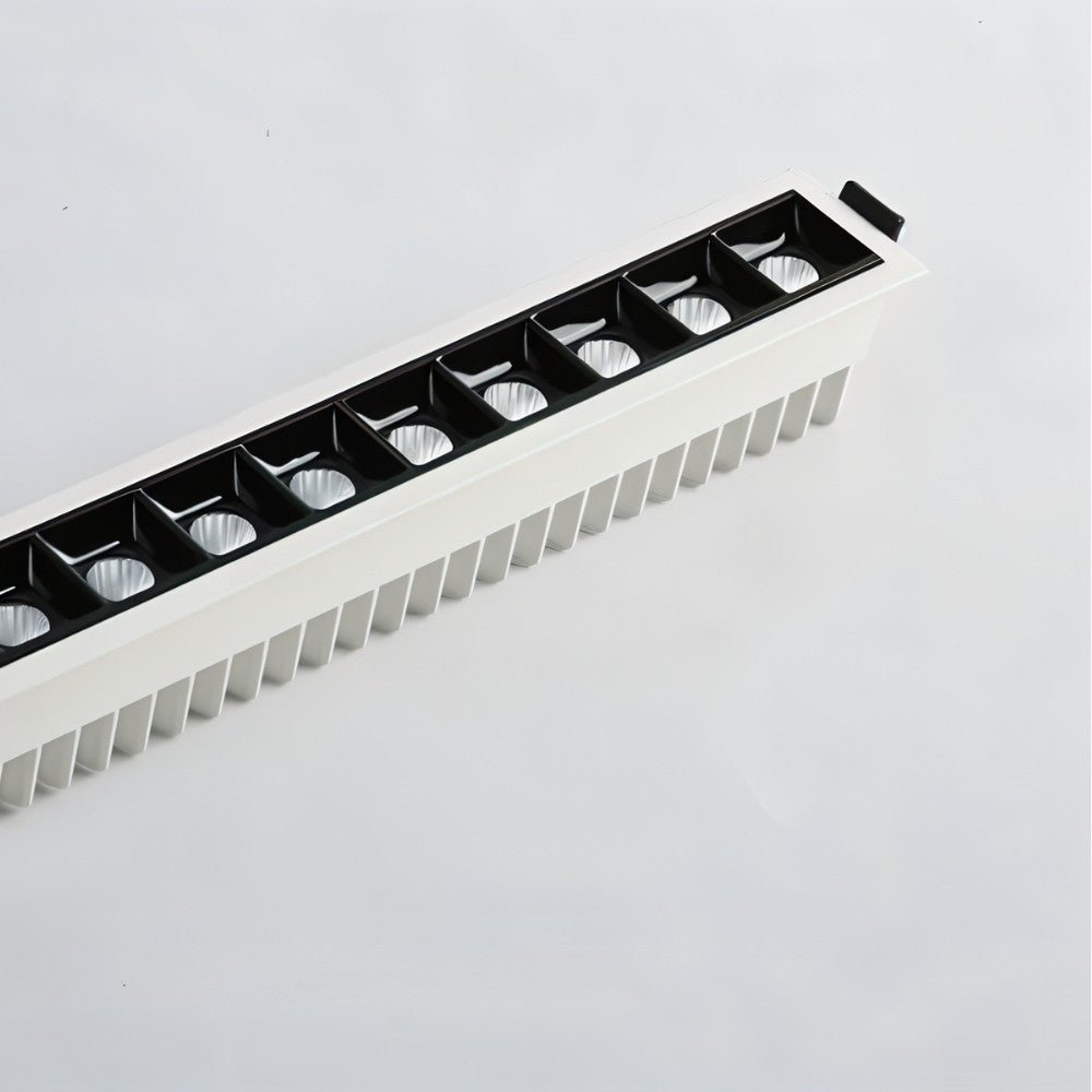 Clérachic long white linear downlight seen at an angle, with a finned aluminium heatsink behind a row of black square reflectors.